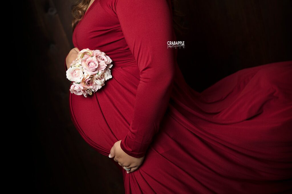 Boston area maternity photographer capturing close up of baby bump in red dress with flowers