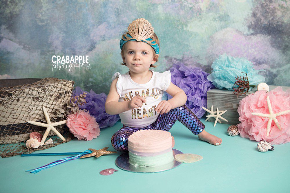 Mermaid themed cake smash portraits using blue, purple, and pink as a color palette.
