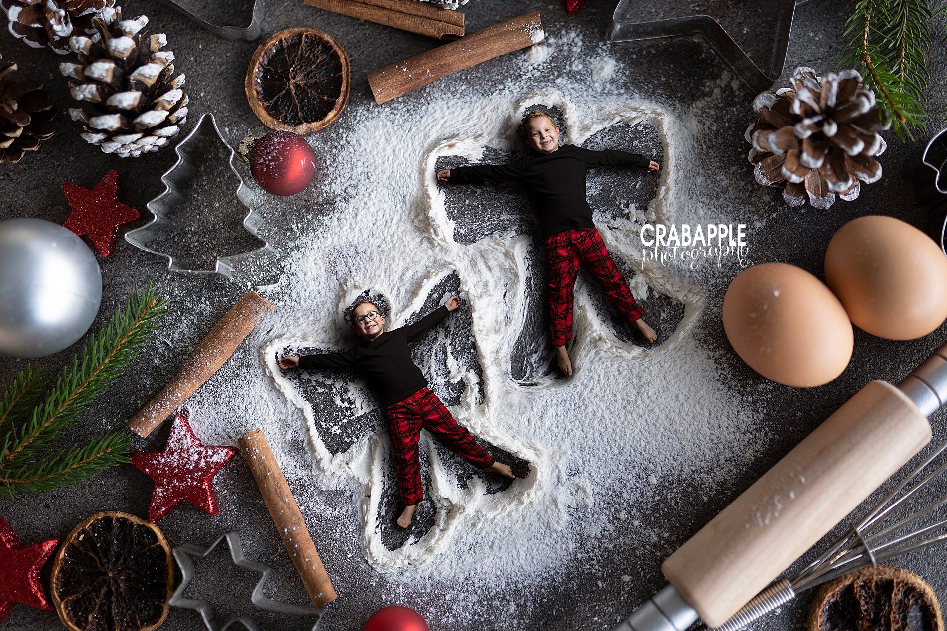 Digital Composite Christmas Photo including two siblings making snow angels in baking flower surrounded by other enlarged baking tools and ingredients. Andover Christmas Photos