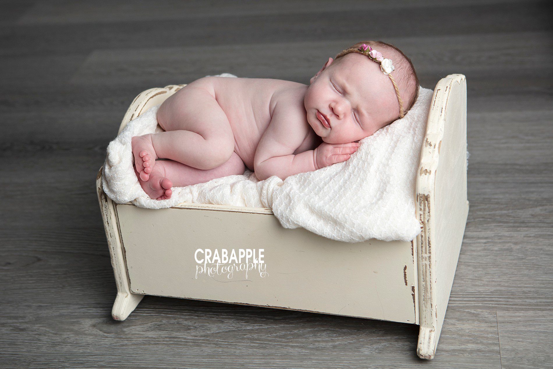 Newborn baby photo on rustic wooden bassinet