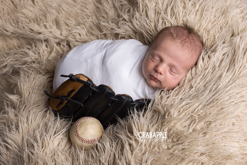 Classic newborn baby boy photo with baseball and glove. Baby and props are on top of a tan fur. 