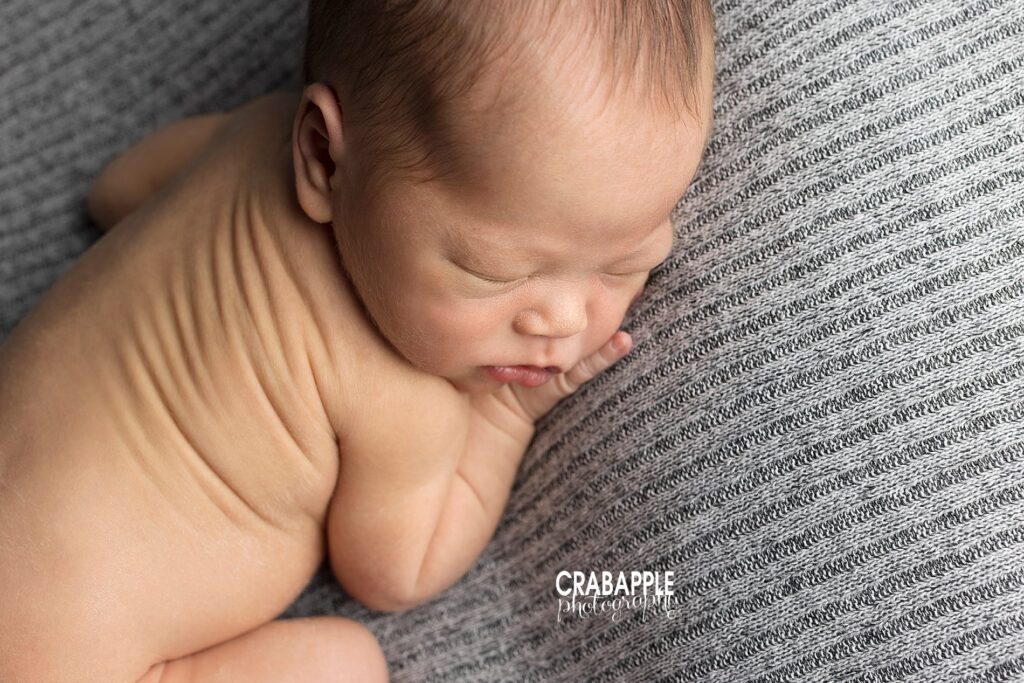 Newborn baby boy portrait taken from above as baby boy lays on a gray knit blanket.