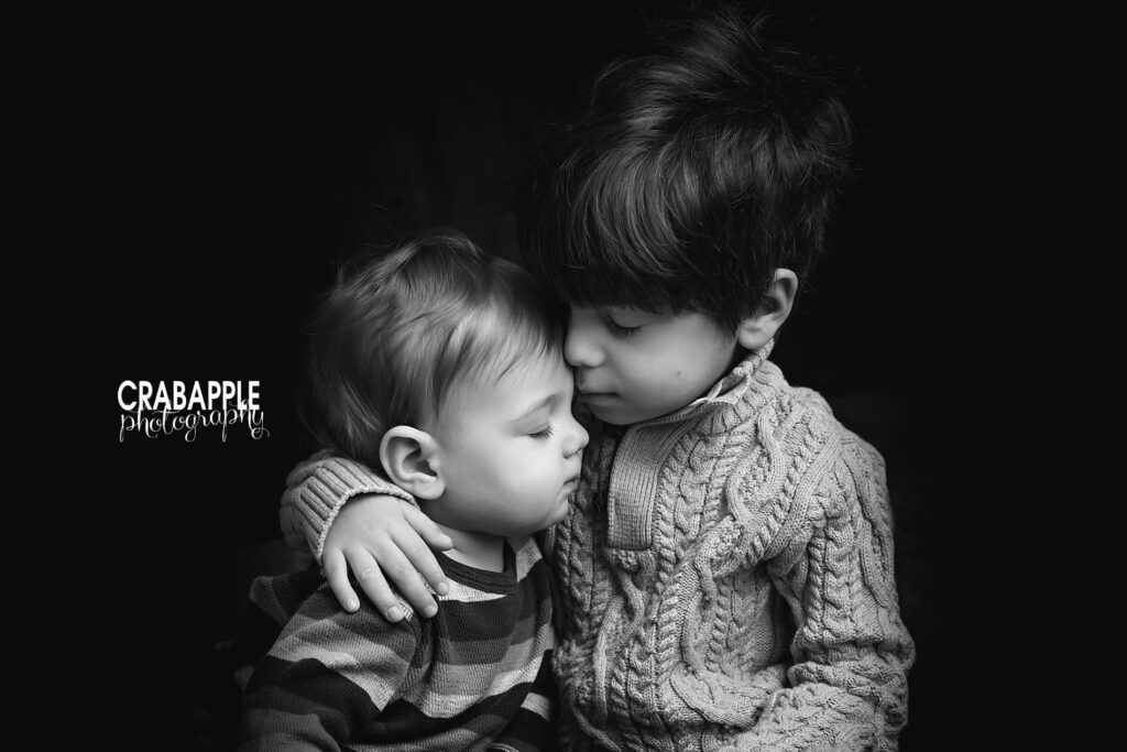 A black and white portrait of two young brothers embracing, eyes closed.