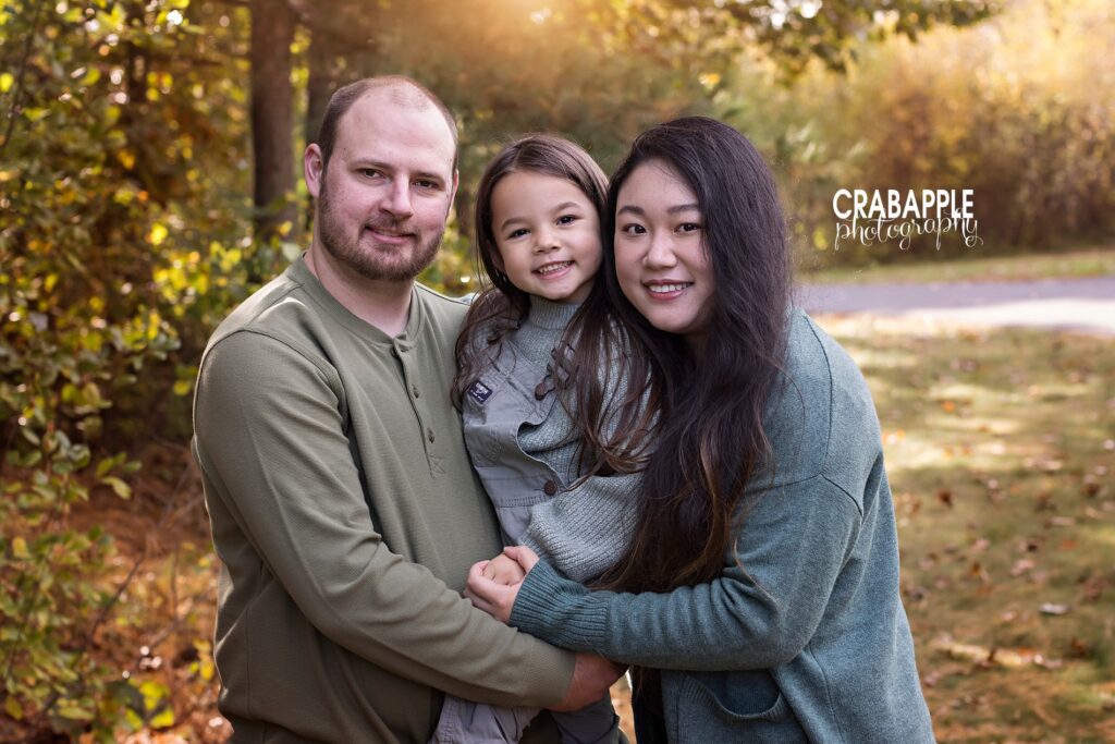 Family photo inspiration for fall. A family of three embraces each other while standing outside.