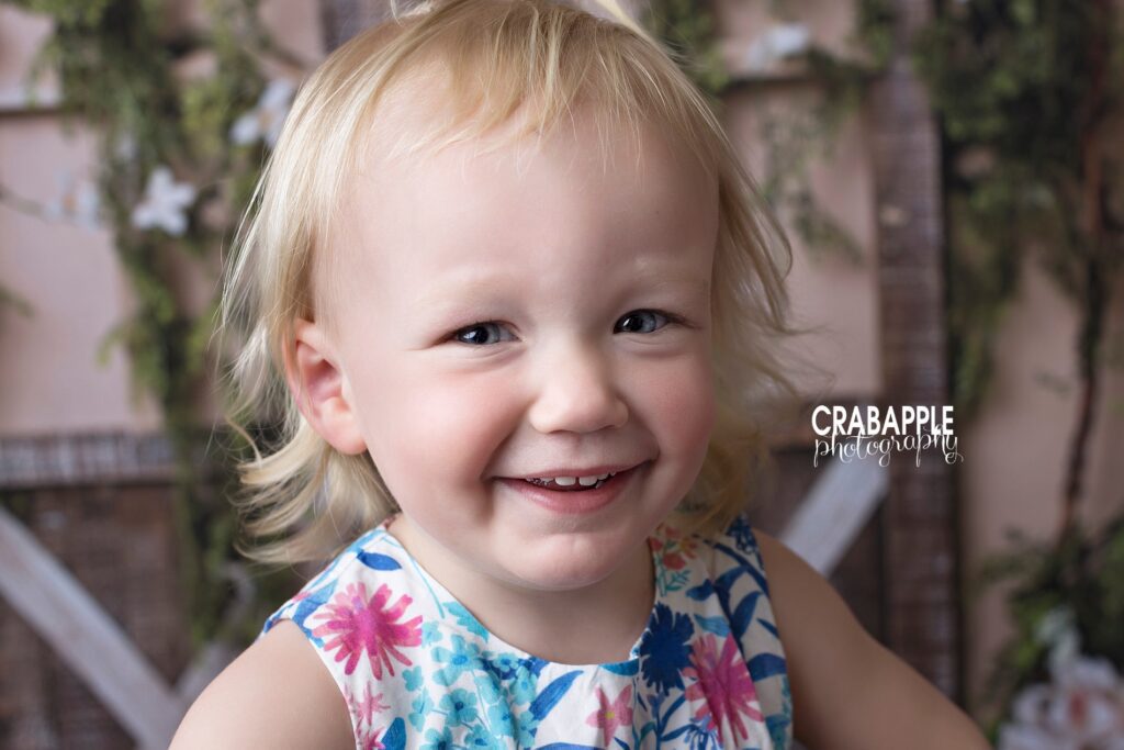 Close up portrait of a baby girl in a floral multicolored dress.