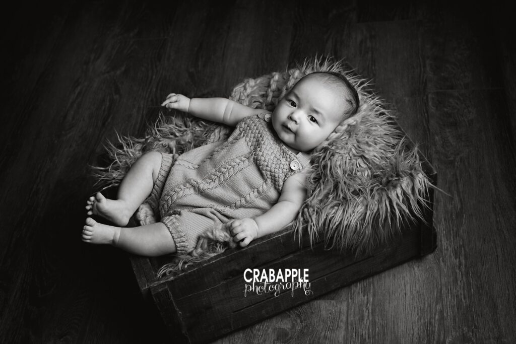 Black and white baby photography ideas using wooden crate and fur as props.