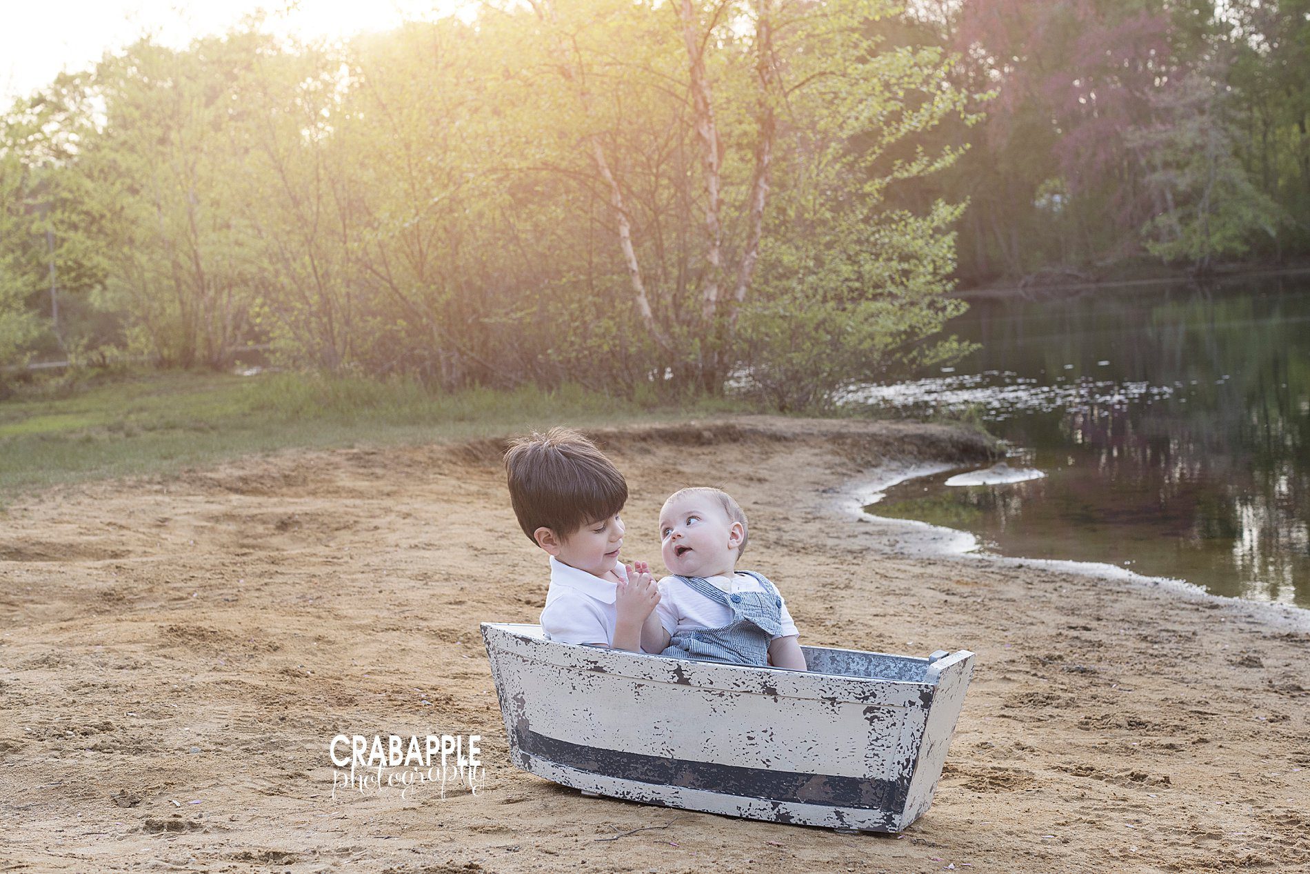 Brother photos using a tiny vintage inspired boat prop on the banks of a lake.