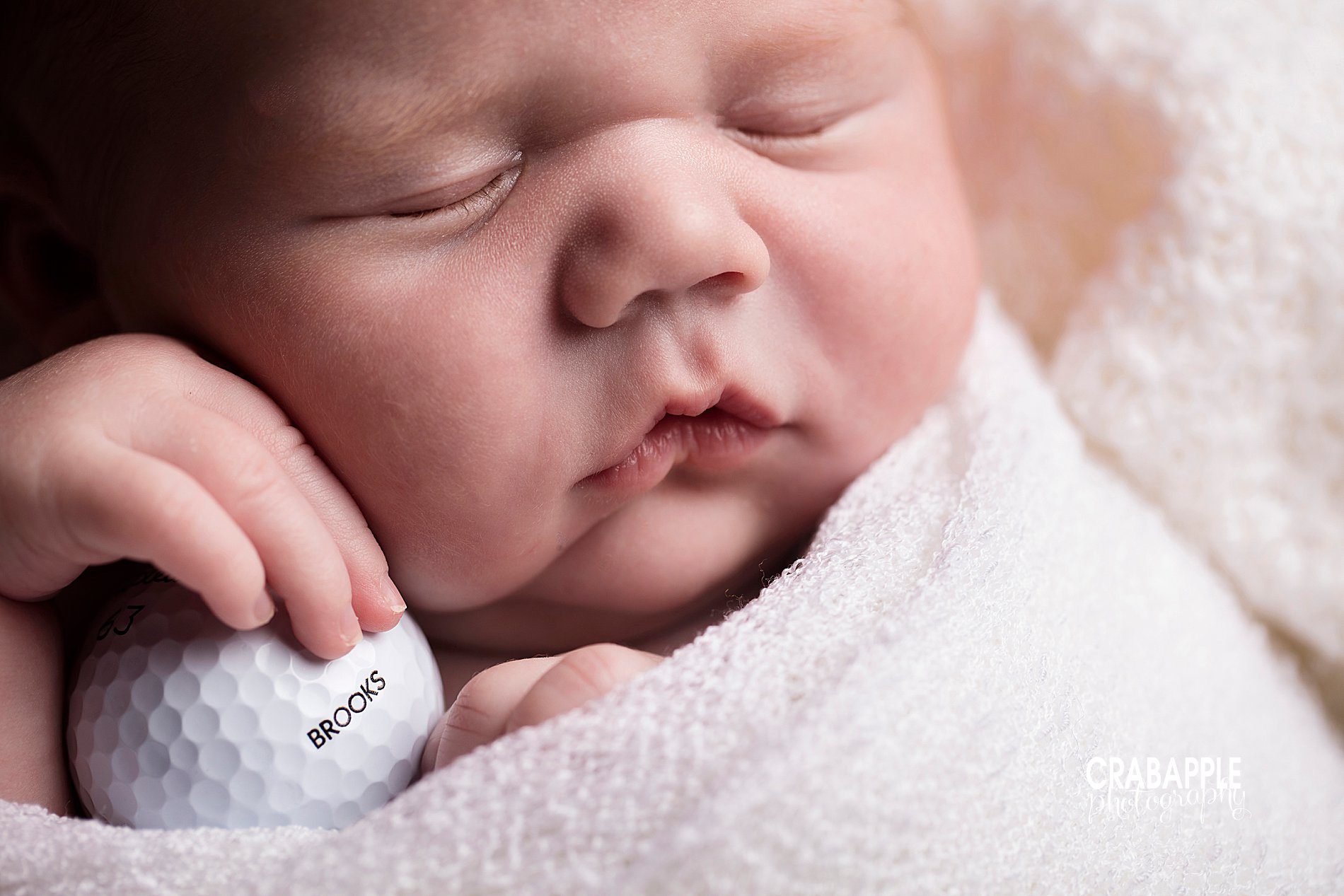 Close up newborn photos of baby's face and features including personalized golf ball with baby's name