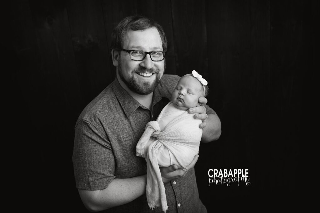Black and white portrait of dad with newborn baby girl.