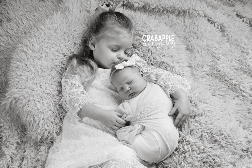 Black and white portraits of newborn and toddler sisters.
