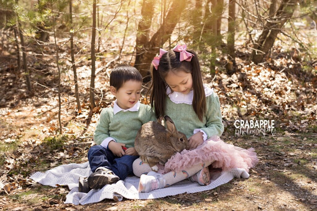 Sibling photos including older sister and younger brother in matching light green sweaters. Both are looking down at the live bunny in the little girl's lap.