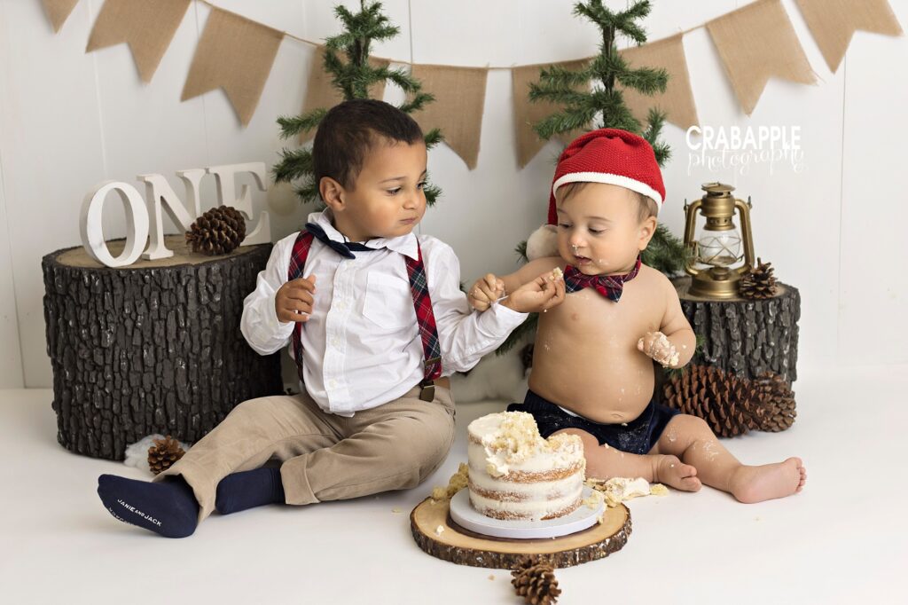 Cake smash photo ideas with older sibling sharing cake with the baby.
