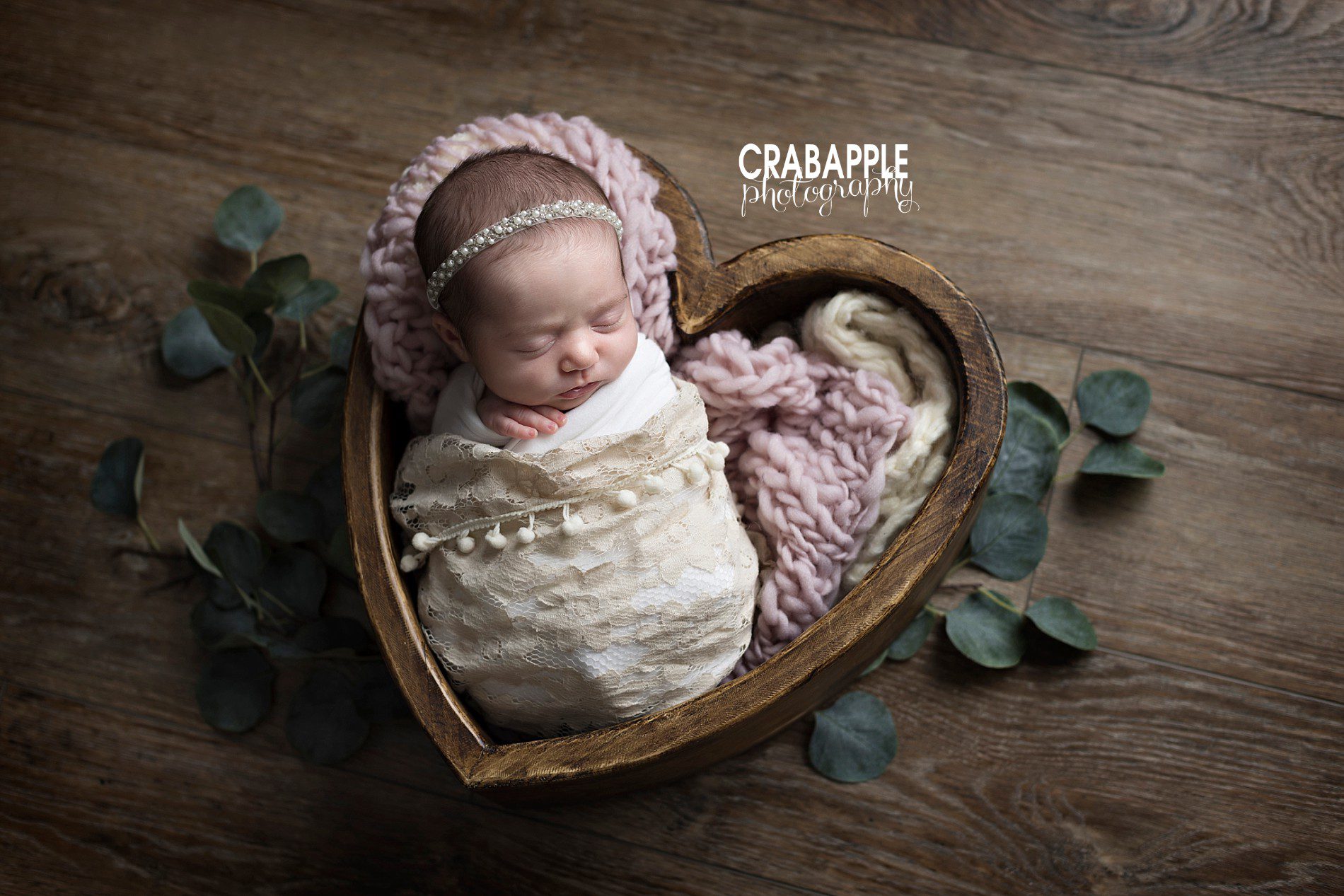 Ideas for styling newborn photos using faux greenery, wooden heart shaped bowl, chunky knit blankets, lace, headbands.