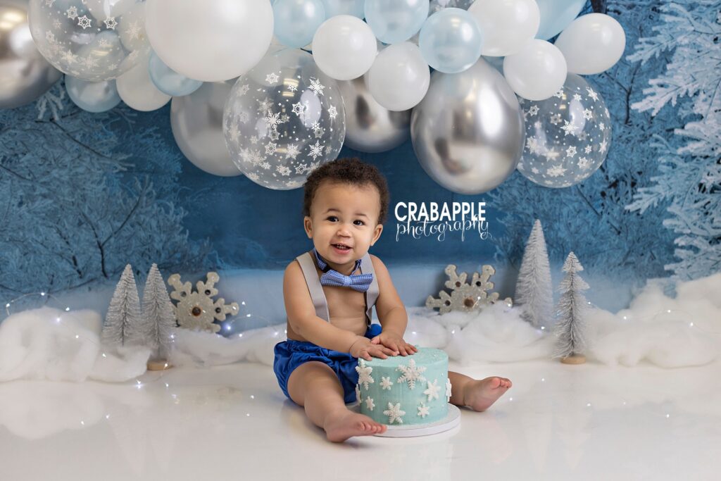 Winter ONEderland cake smash with snowy woodland backdrop and snowflake cake
