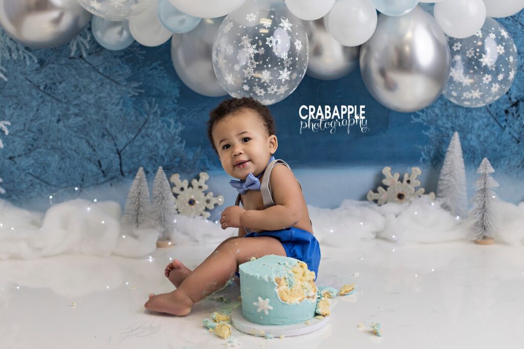First birthday boy celebrating with Winter ONEderland themed cake smash setup
