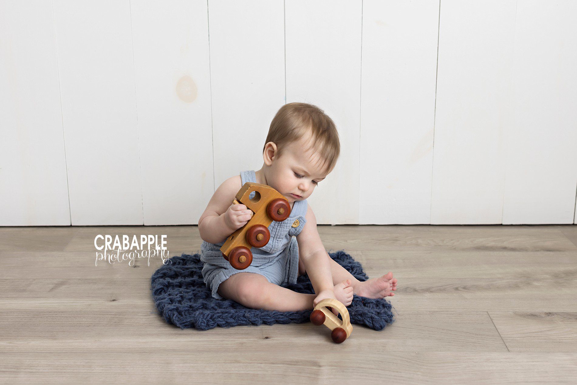 portrait of baby playing with wooden car and truck toy