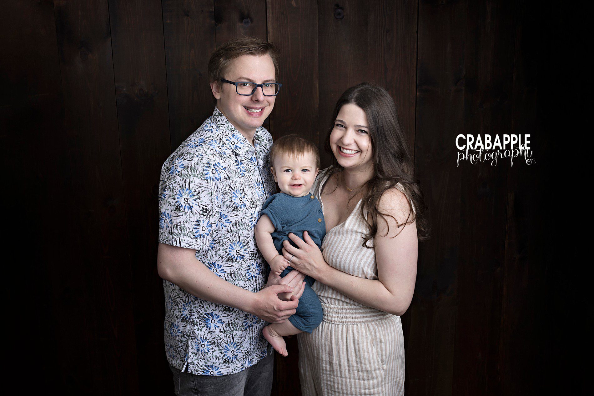 family photos in front of dark wood backdrop