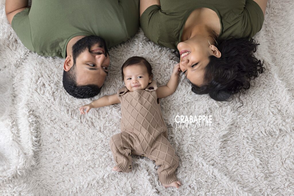 smiling three month old baby boy with parents during milestone session
