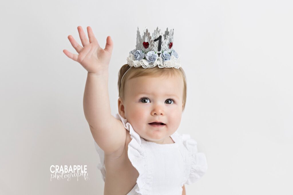 baby girl in neutral outfit and birthday crown during timeless first birthday photos
