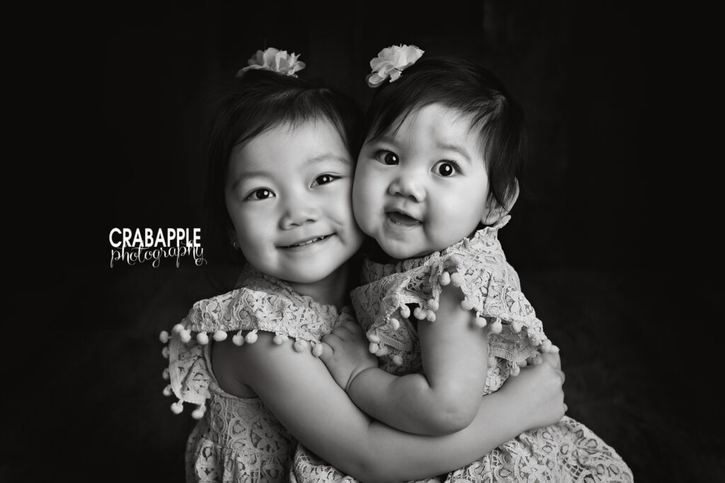 3 year old sister hugs 1 year old sister during Quincy MA birthday portraits