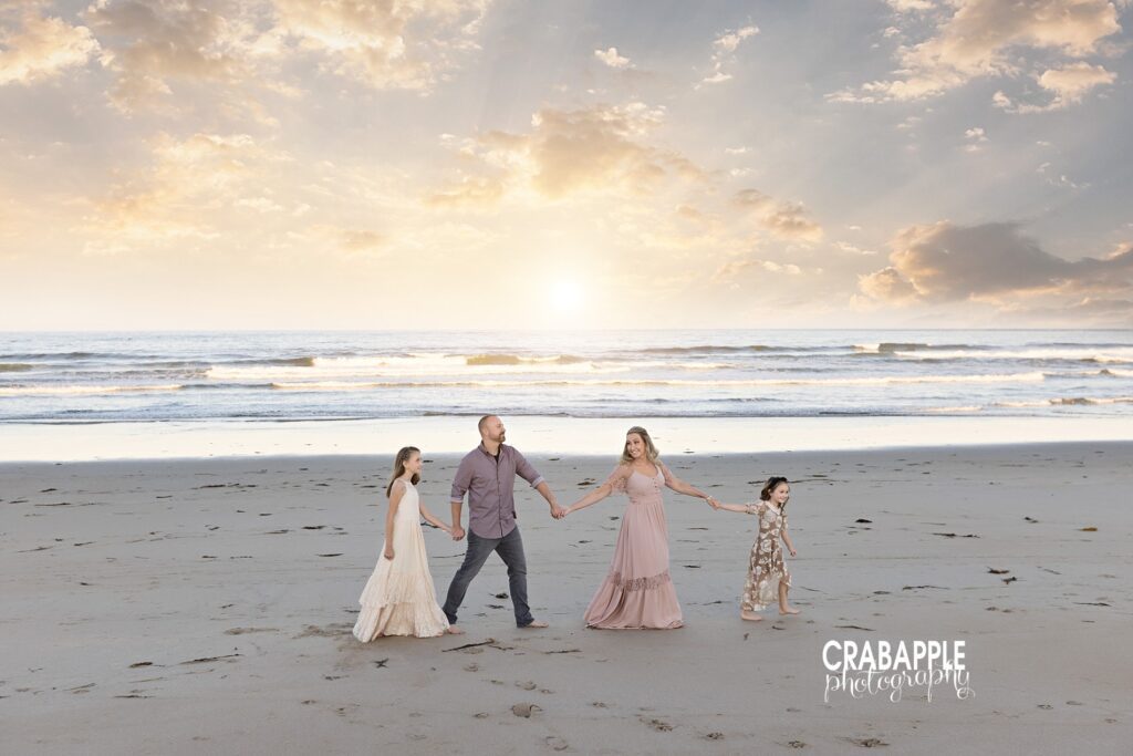 Family of four strolls along the sandy beach during family portraits