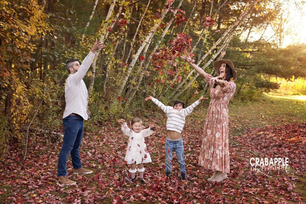 Family of four plays in the leaves during family portraits in fall