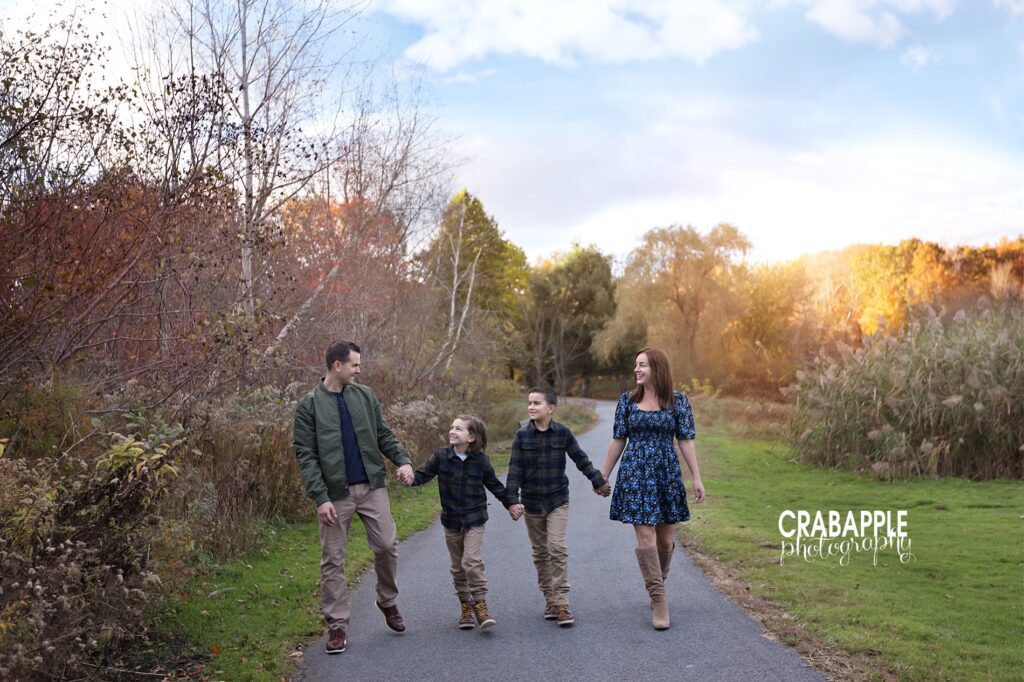 Family of four walk through a park hand in hand during fall photos
