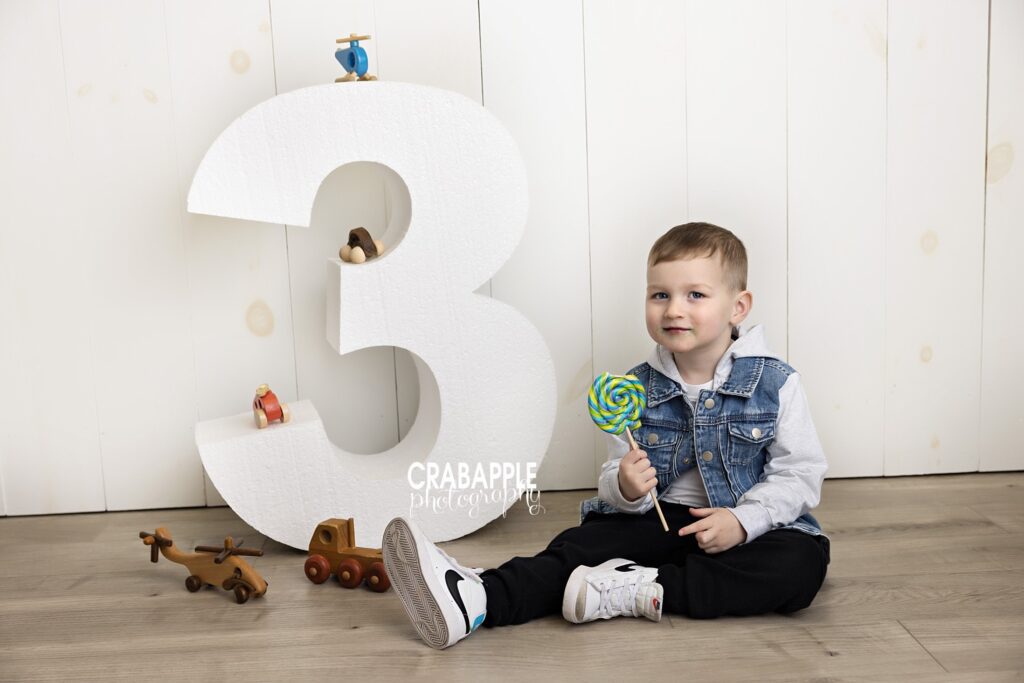 Toddler photos with giant wooden 3, toys, and lollipop