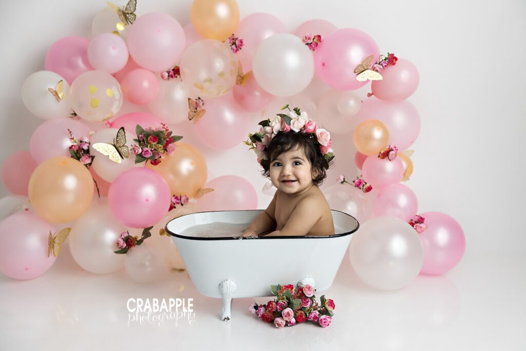 1 year old girl in metal bath tub during first birthday cake smash and splash session near Quincy MA