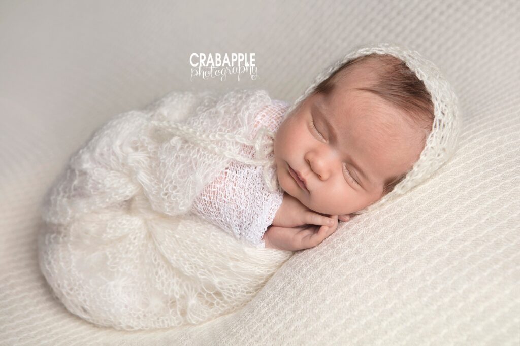 Newborn swaddled in cream on soft knit blanket 