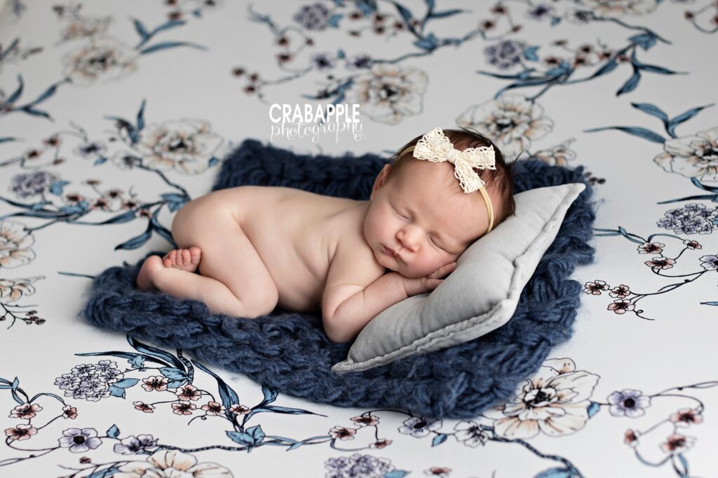 Newborn baby girl on blue floral blanket with headband, Massachusetts newborn portrait session
