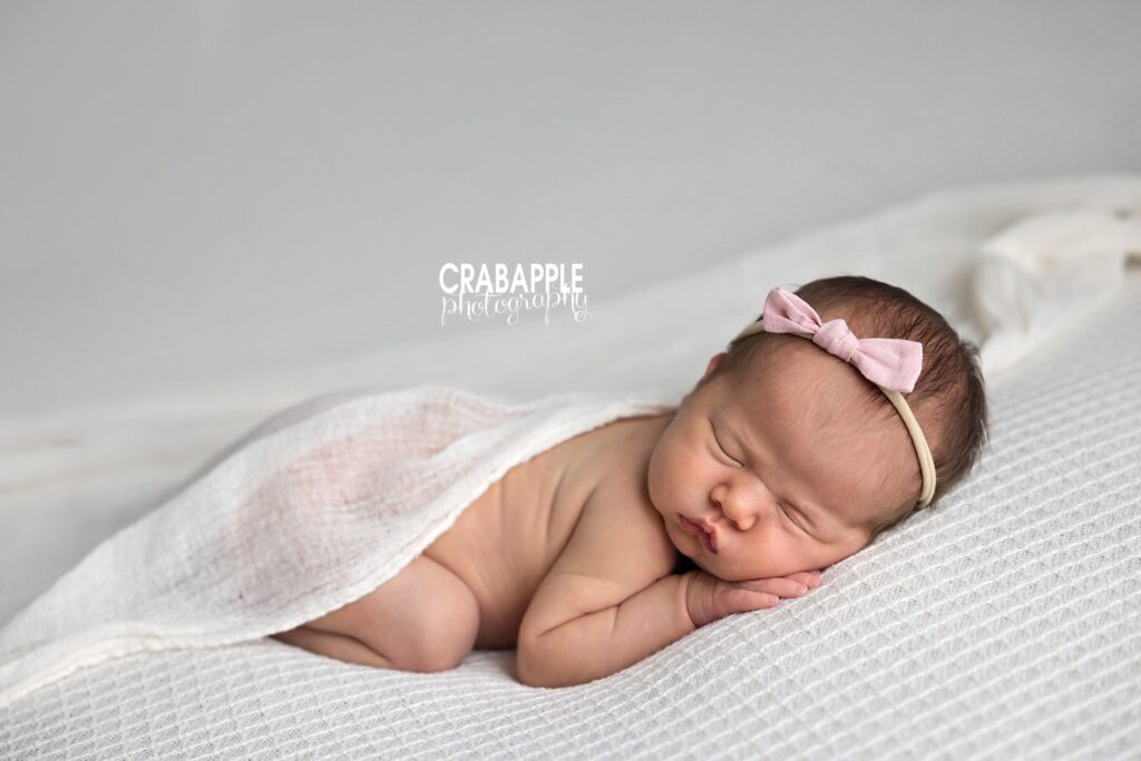 Newborn girl sleeping with pink bow and delicate wrap – feminine newborn photographer MA

