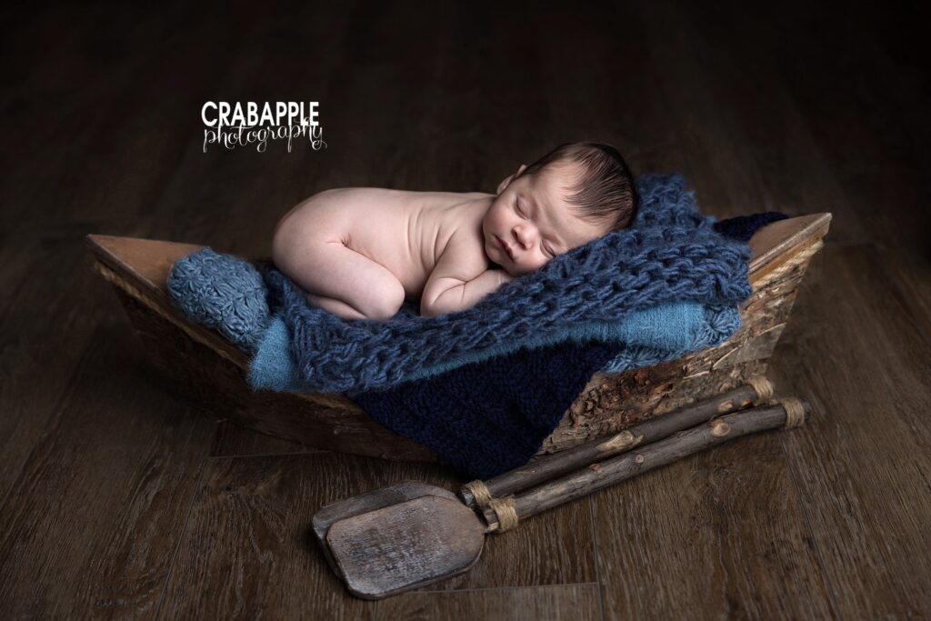 Rustic Canoe Newborn Photography Newborn baby posed inside a rustic wooden canoe for a timeless portrait