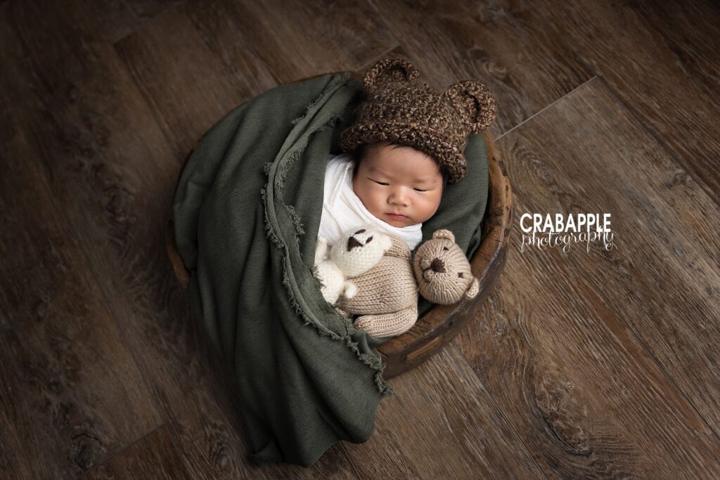 Newborn dressed in teddy bear bonnet and snuggled in green wrap  creative MA baby photo
