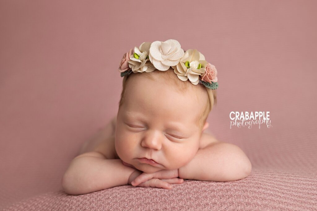 Newborn girl with floral headband posed on pink backdrop – Massachusetts baby photography

