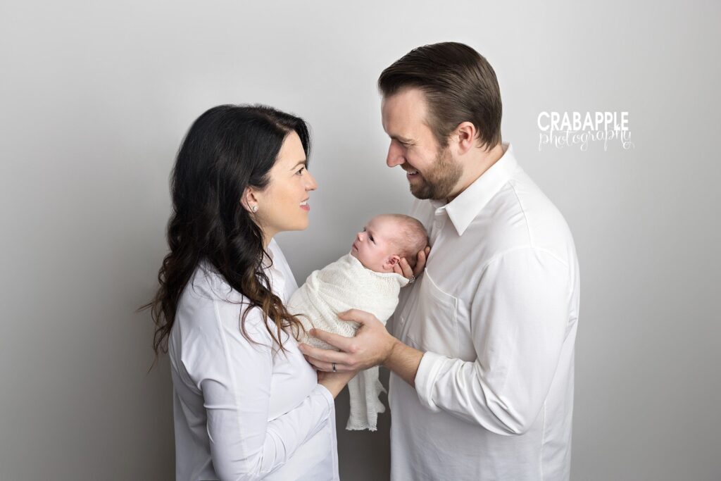 Parents smiling at each other while holding baby – family newborn session Boston
