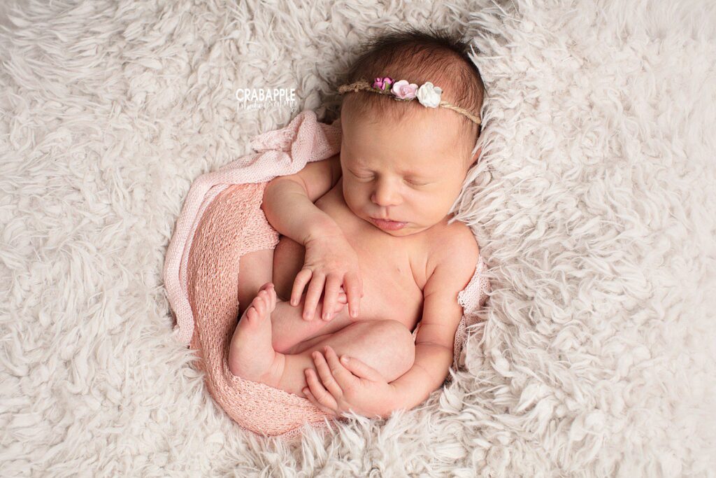 Newborn wrapped in pink knit blanket on soft blush wrap 


