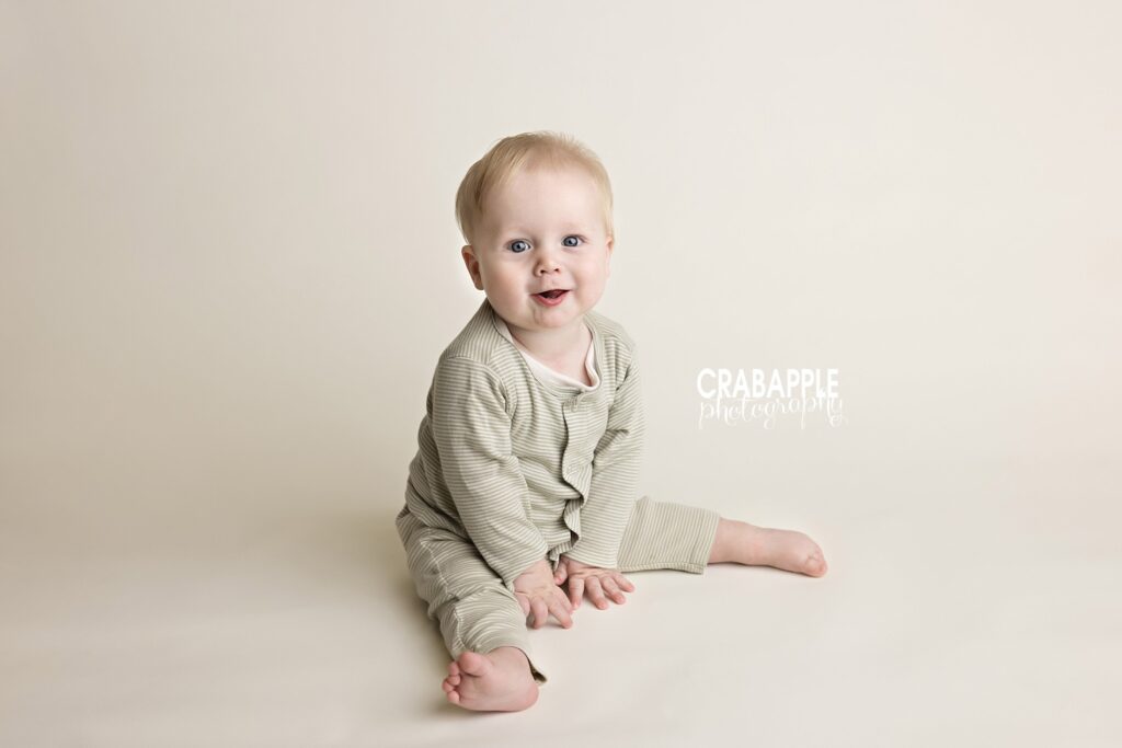 smiling baby boy looking at camera, with a simple cream backdrop