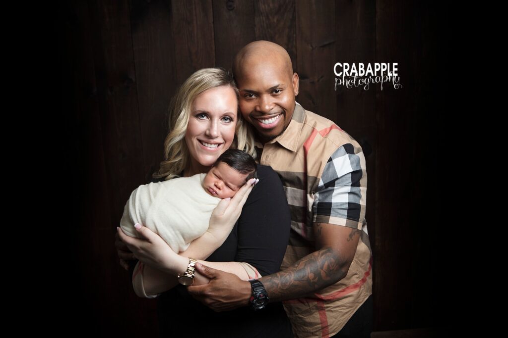Parents smiling with newborn during studio family session 

