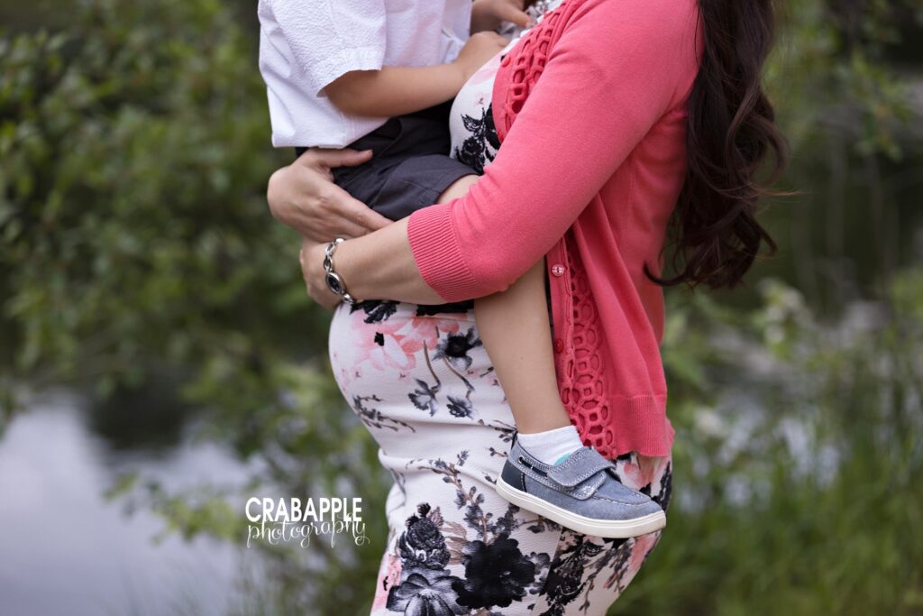Outdoor maternity photo with mom holding toddler against her bump