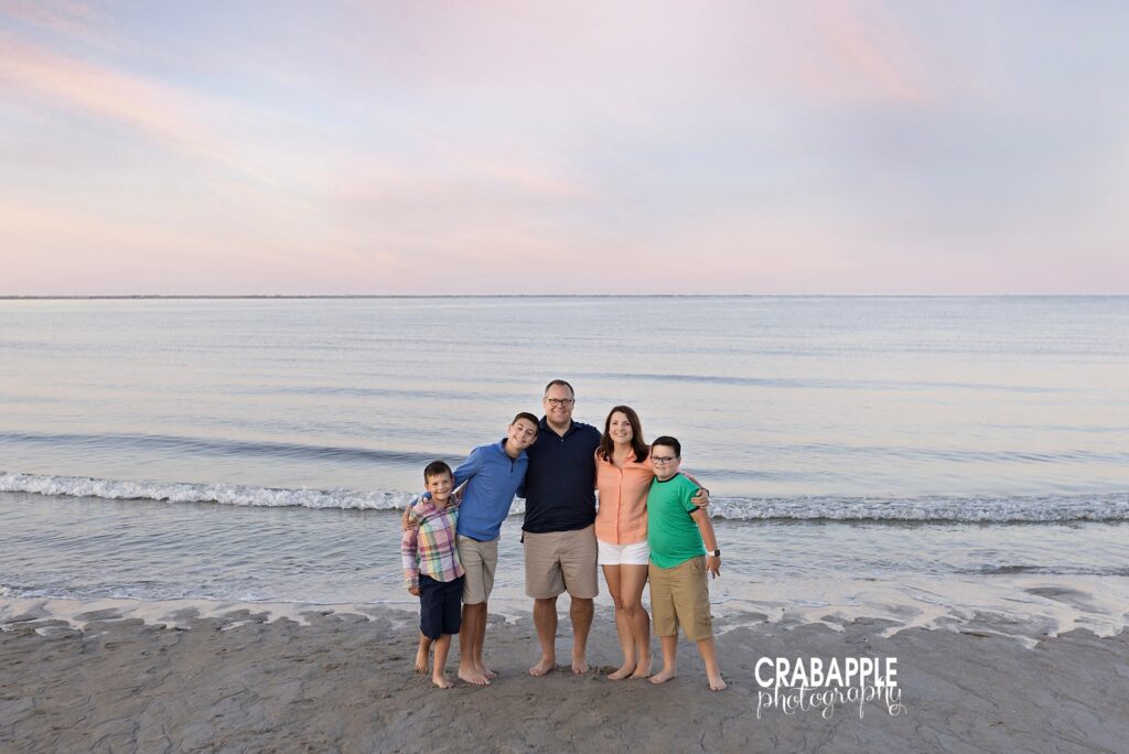 Family of five smiling together on the shoreline at Crane Beach during golden hour