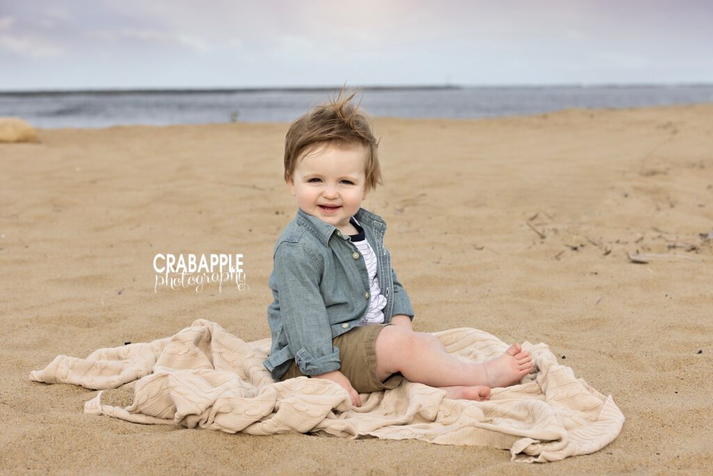 Toddler sitting barefoot in the sand during family beach photos near Boston a great image of childhood at the beach