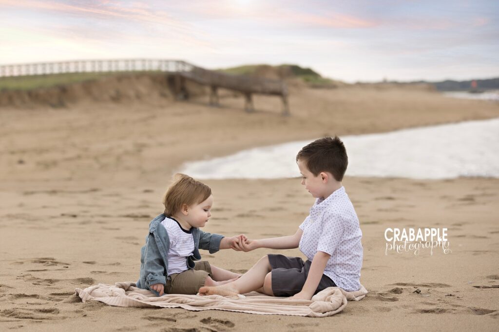 Two young brothers exploring the shoreline at sunset and showing childhood at the beach

