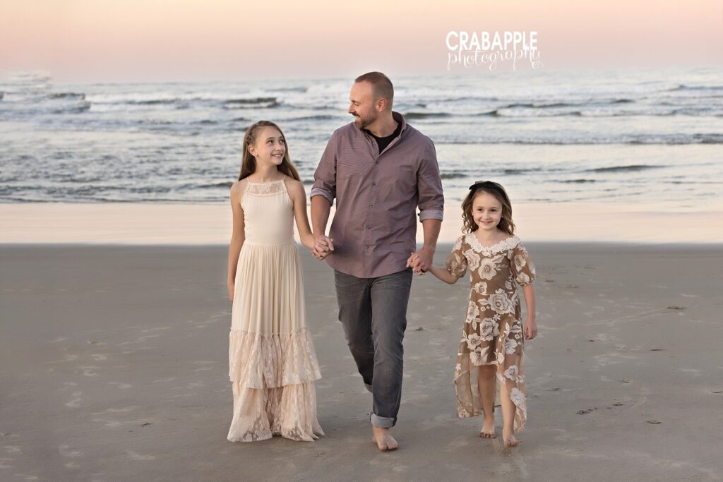 Father walking hand-in-hand with daughters along Salisbury Beach