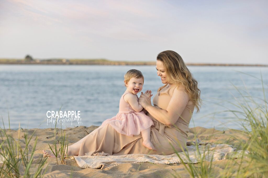 Laughing mother and daughter captured candidly on Plum Island’s sandy beach for a mommy and me photography session north of Boston
