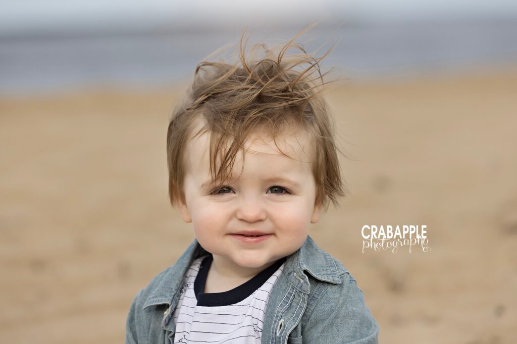 Close-up of smiling toddler with windblown hair at Plum Island by a family and child photographer