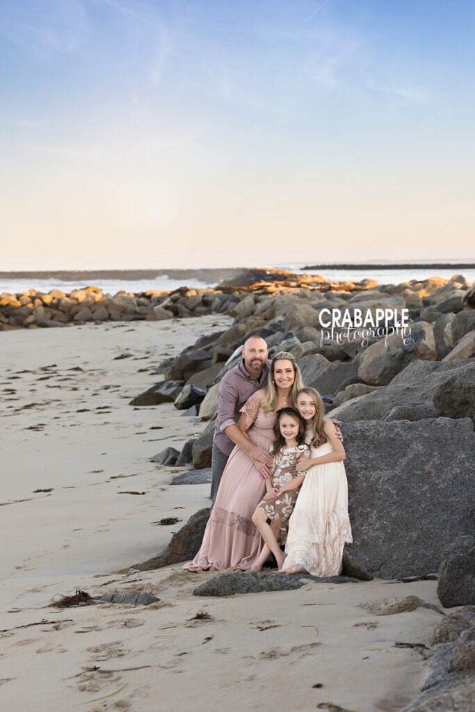 Family snuggled on rocks near the ocean at Salisbury Beach