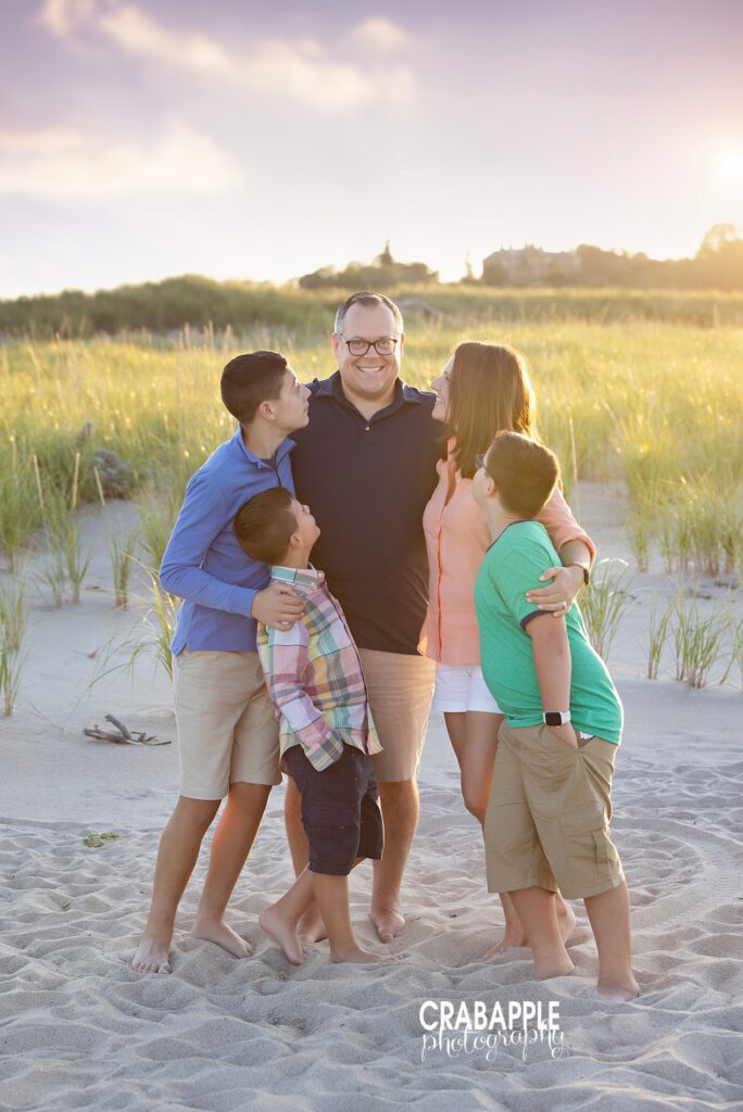 Family group hug in dune grass with golden sunset at Crane Beach in Ipswich MA