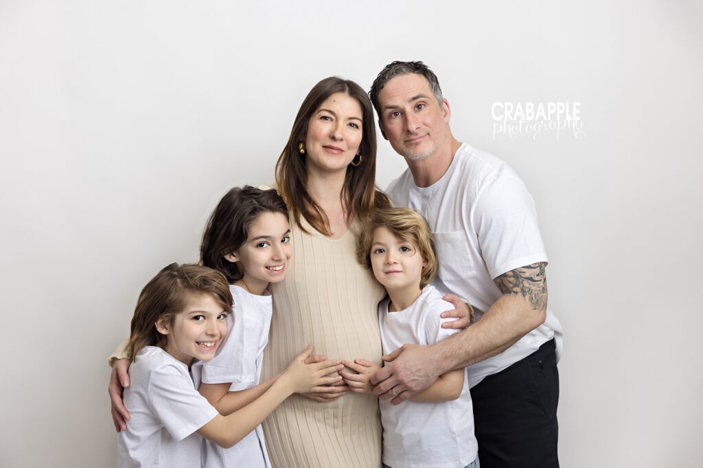 Full family pregnancy portrait with mom, dad, and three kids all embracing the belly from a Maternity photo studio in Andover MA