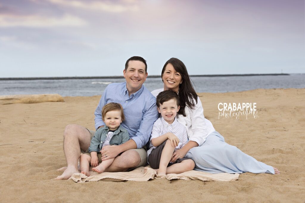Family sitting on sand together during sunset natural family photography session on the North Shore